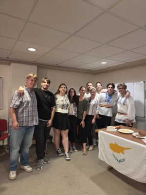 Group of participants standing together during the Cyprus cultural night, with traditional clothing and local food displayed.