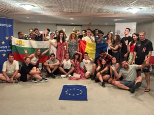 Participants of the YETF ‘Mastering the Digital Landscape’ project posing together indoors with national flags and an EU flag on the floor, celebrating teamwork and European cooperation.