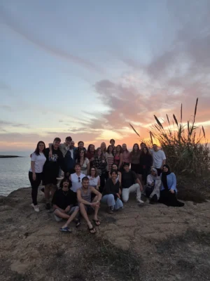 Participants gathered on a seaside rock at sunset during the Pause and Breathe mindfulness youth exchange.