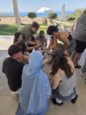 Participants kneeling in a circle working together during a mindfulness-based group coordination exercise.