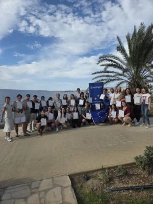 Group of participants holding certificates by the seaside during the final ceremony of the mindfulness youth exchange.