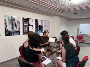 A group of youth workers sitting indoors discussing photography-based educational methods during the YETF training course.