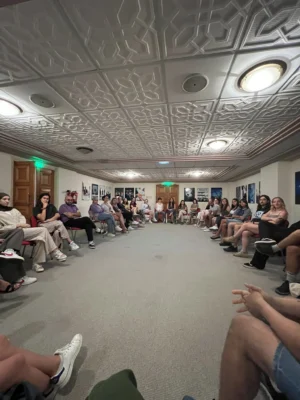 Participants of the YETF photography course sitting in a wide circle, engaging in a reflective group discussion indoors.