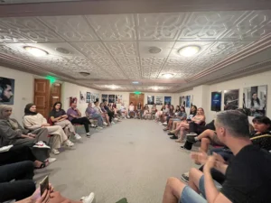 A large circle of youth workers sitting indoors during a group discussion at the YETF photography training course.